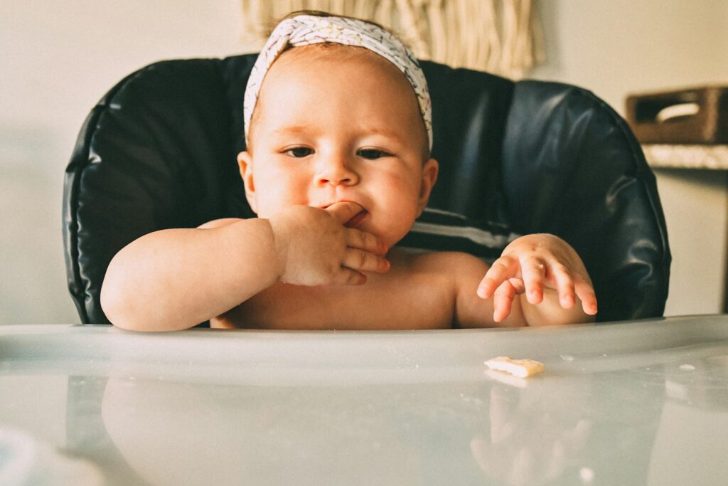 Baby sitzt im Hochstuhl und isst selbst – Baby-led Weaning im Alltag