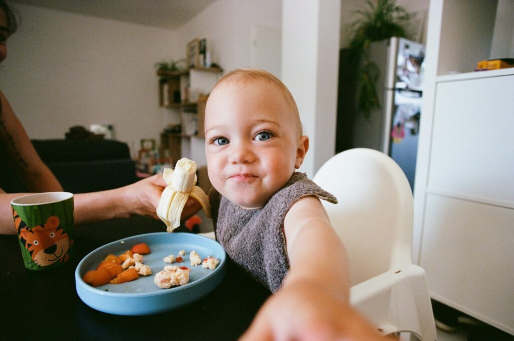 Baby am Tisch mit einem Teller Essen – geeignete Lebensmittel für Baby-led Weaning