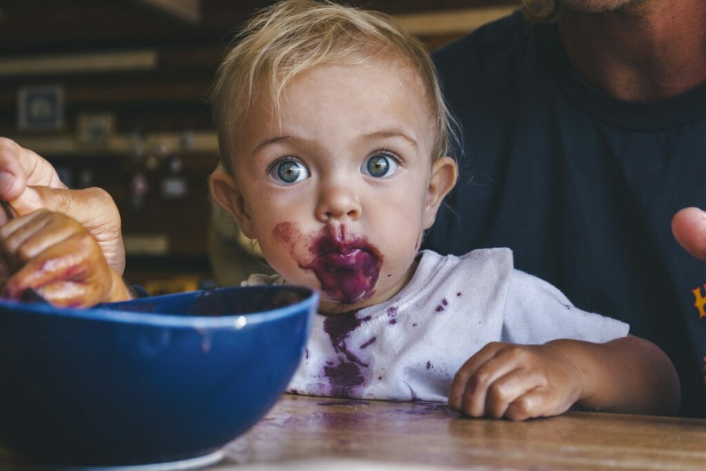 Kleines Mädchen mit Essen im Gesicht – Baby-led Weaning darf kleckern