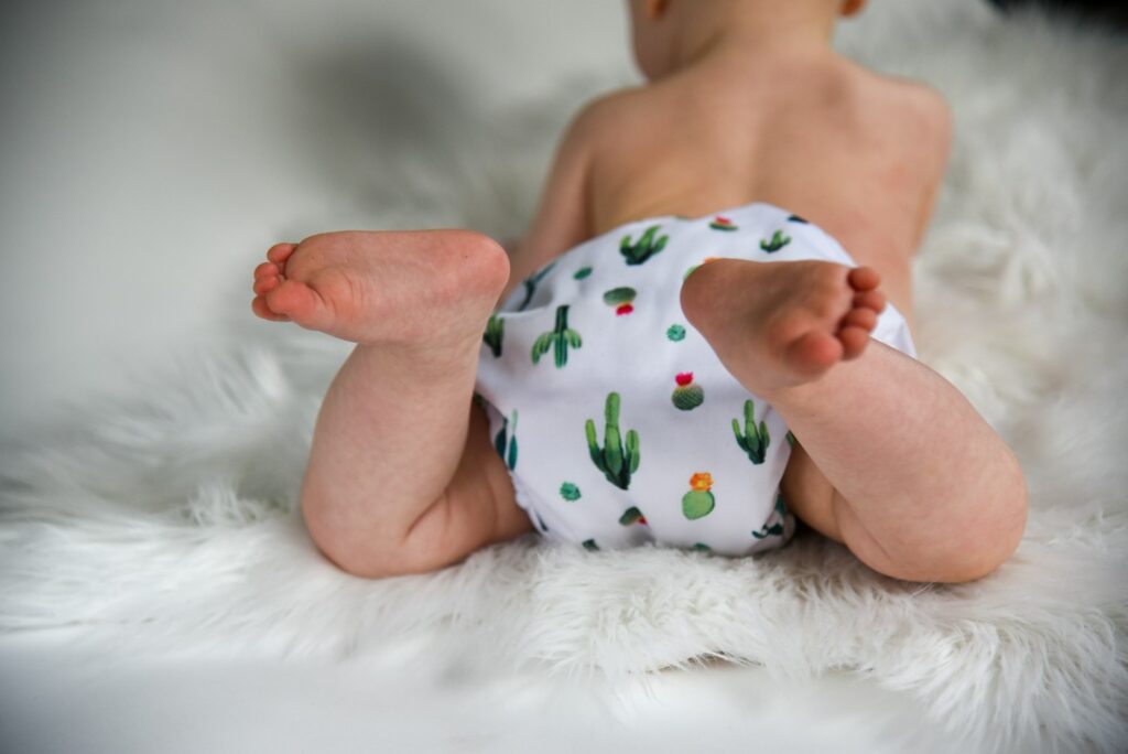 Nach dem Baby wickeln: Kind in einer bunt bedruckten Windel