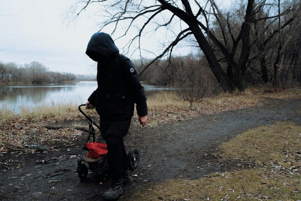 Spaziergang mit Kinderwagen am Fluss, bei dem Babyhaut im Winter gut geschützt sein sollte