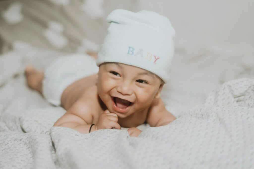 Baby mit weißer Mütze, dessen Babyhaut im Winter besondere Pflege braucht