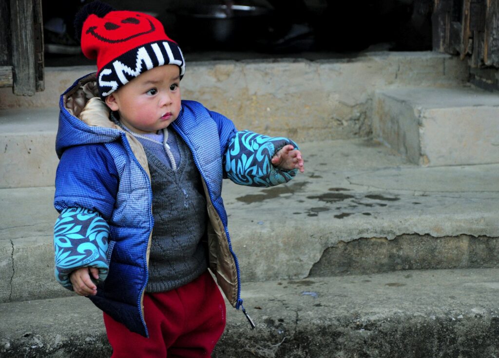 Babyhaut im Winter schützen: Kleinkind in warmer Winterjacke und Mütze im Schnee