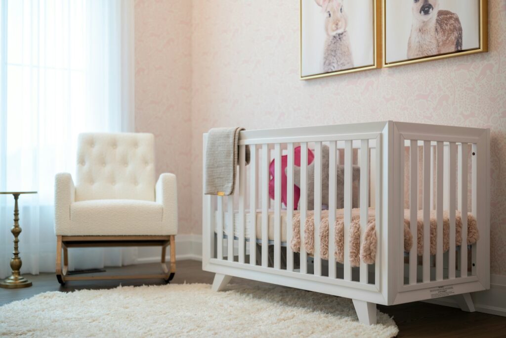 Kinderzimmer mit Babybett und Sessel als Teil der Erstausstattung Baby