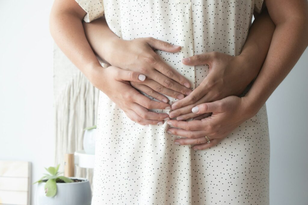Paar legt die Hände auf den Babybauch und will gemeinsam einen Geburtsplan schreiben