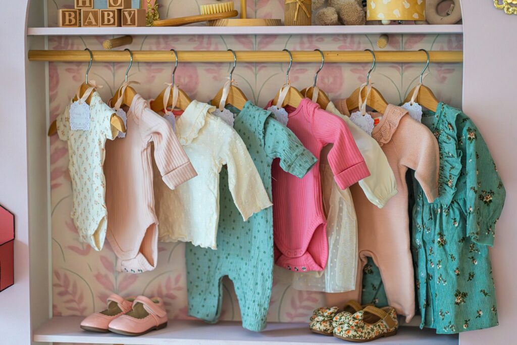 Babykleidung auf einer Kleiderstange – Kliniktasche packen für die Heimfahrt des Babys