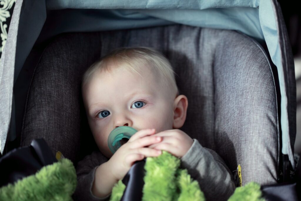 Baby sitzt im grauen Kinderwagen, ein praktischer Begleiter beim Reisen mit Baby