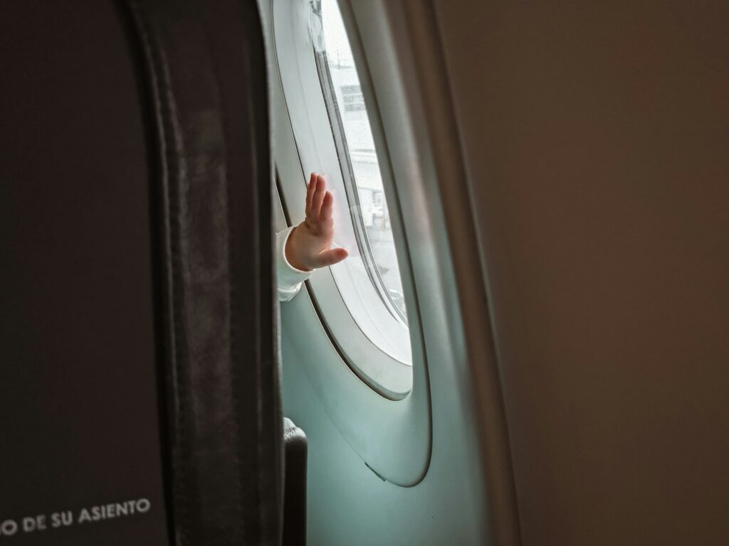 Mutter hält ihr Baby auf dem Sitz im Flugzeug, entspanntes Reisen mit Baby