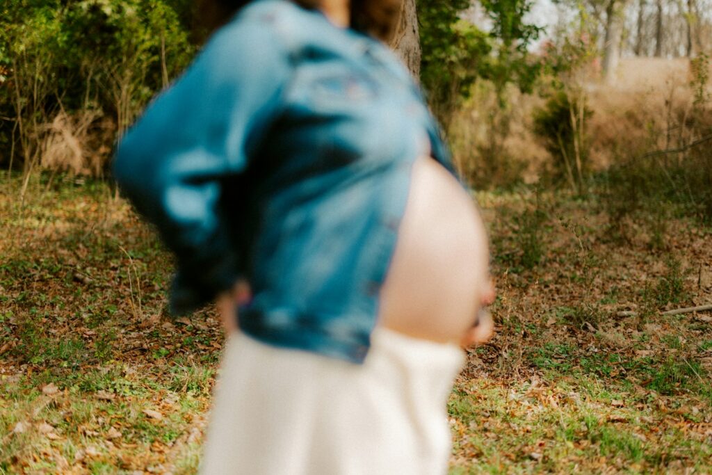 Schwangere Frau in Jeansjacke draußen unterwegs, Spazierengehen als sanfter Sport in der Schwangerschaft