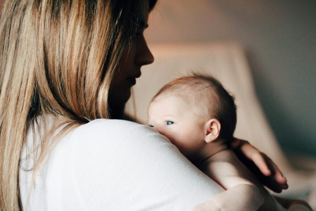 Mutter hält ihr Baby nach dem Stillen im Arm – Stillpositionen im Alltag