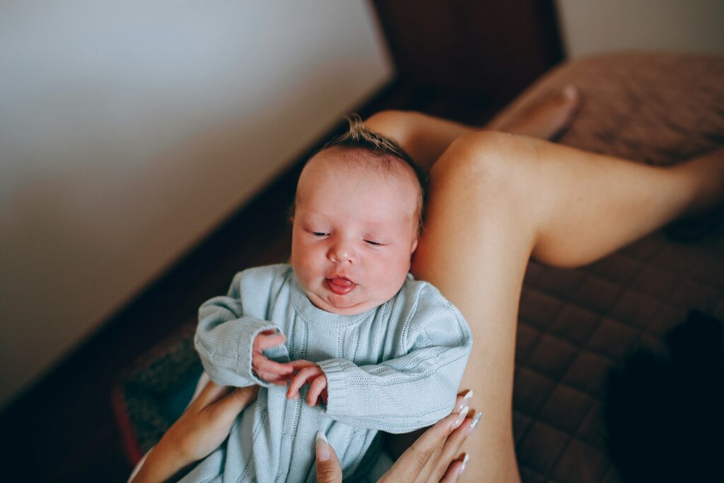 Frau trägt ihr Baby in einer blau-weißen Decke während der Wochen im Wochenbett