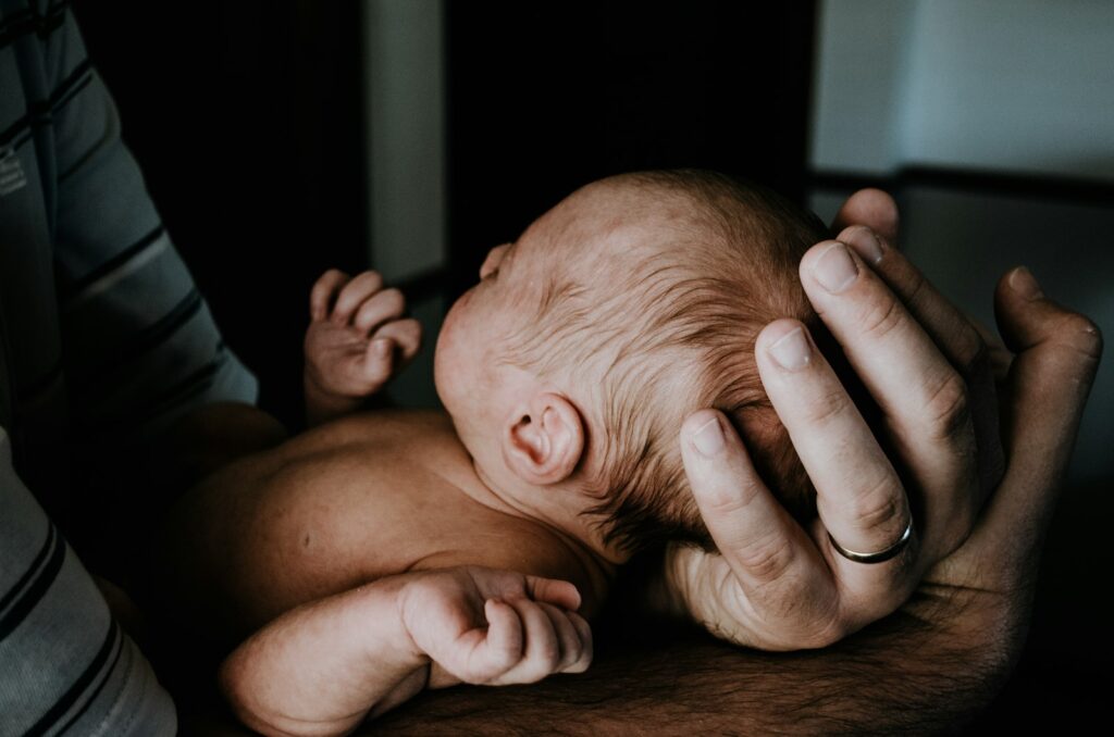 Vater hält sein Baby im Arm und unterstützt die Mutter im Wochenbett