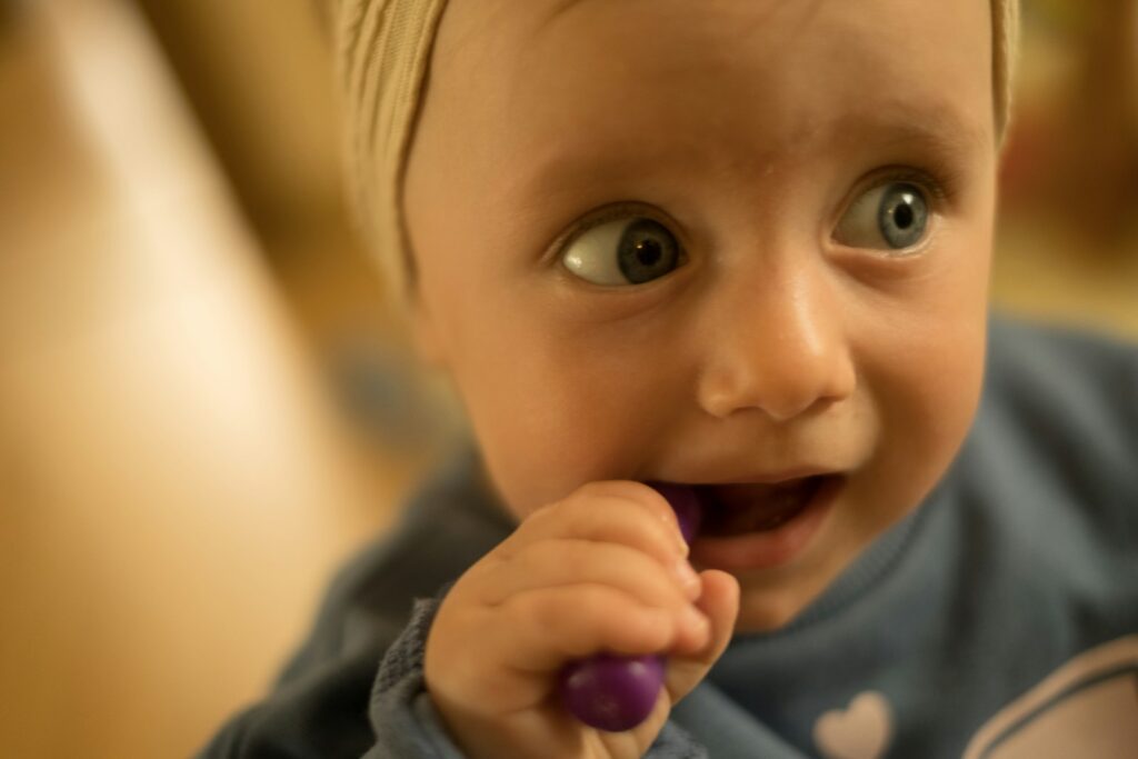 Zahnen beim Baby und Zahnpflege: Baby hält eine Zahnbürste im Mund